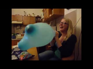 blonde girl blowing up a giant mouse ear balloon until it pops