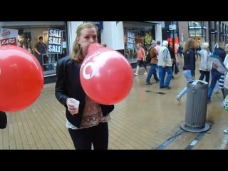 girl popping a tightly blown red balloon in public