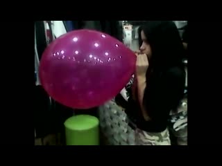 blowing to pop very large balloon in a clothing store